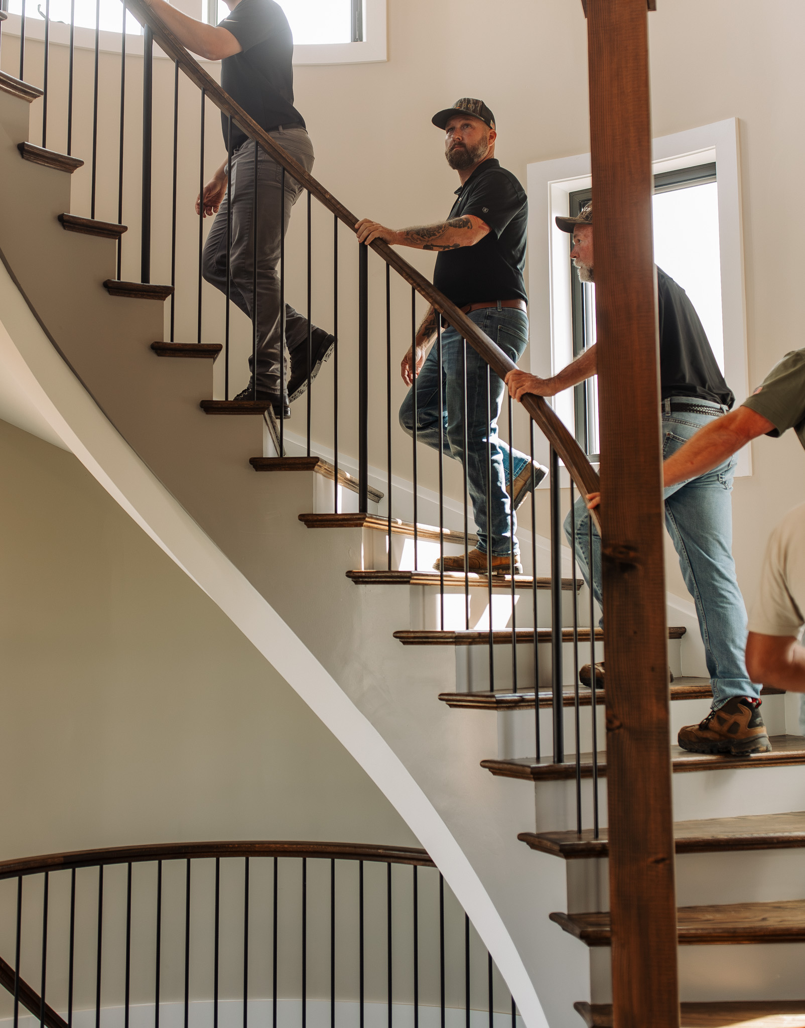 CaseCo Homes team walking up a curved staircase in a luxury custom home